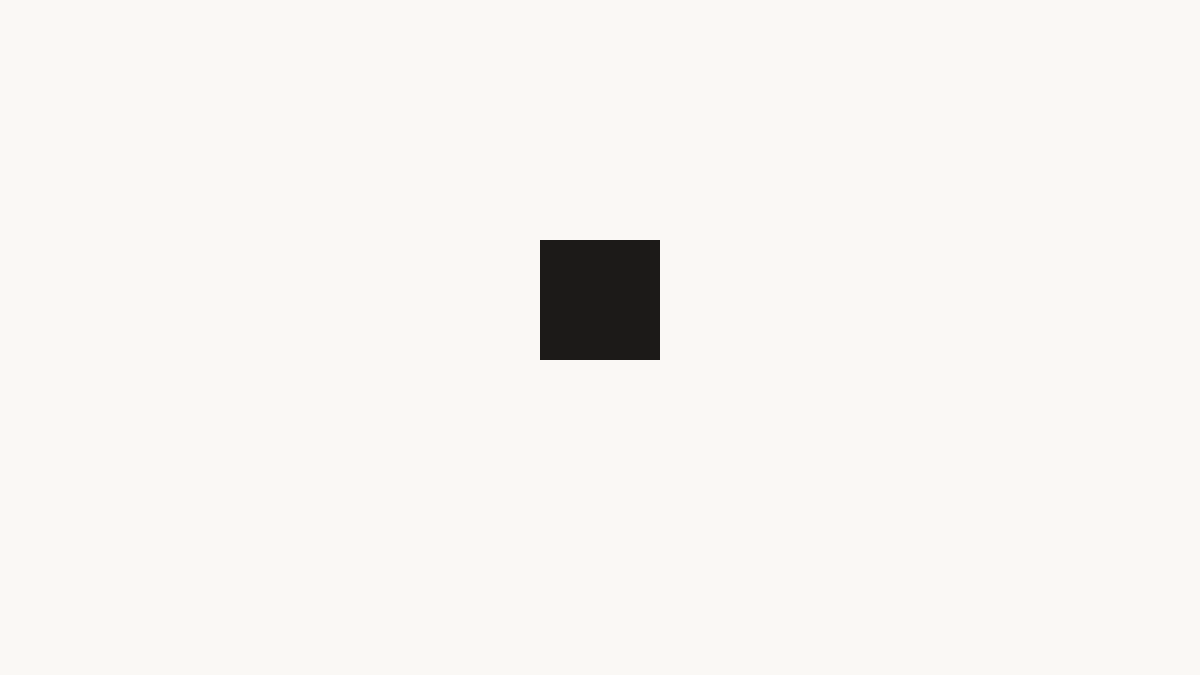 A simple compositional study: a small dark square resting on a warm off-white field, positioned slightly above center.